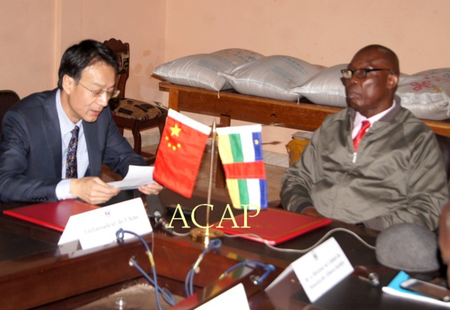 Le Ministre Félix Moloua et l’Ambassadeur Ma Fulin, lors de la signature des documents du don, en arrière plan, des échantillons de sacs de riz