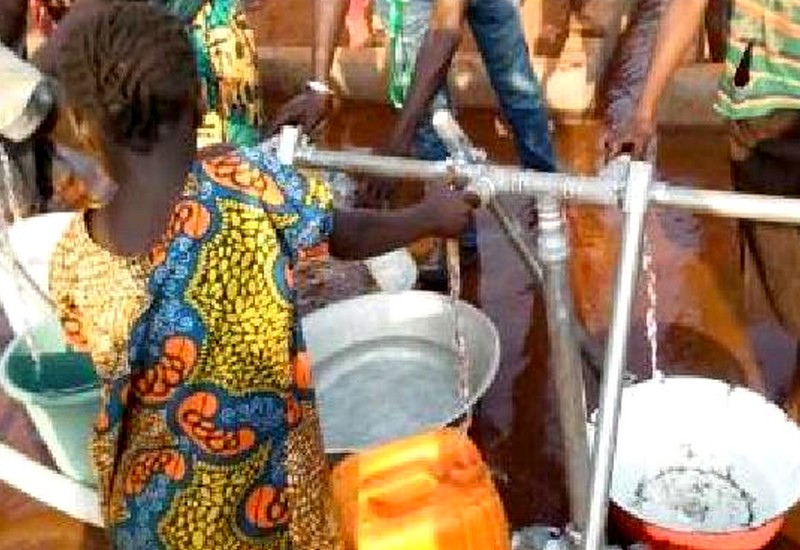 Une jeune fille rempli un bidon d’eau grâce au nouveau réseau gravitaire Oxfam, à Bria, le 29 mars 2019
